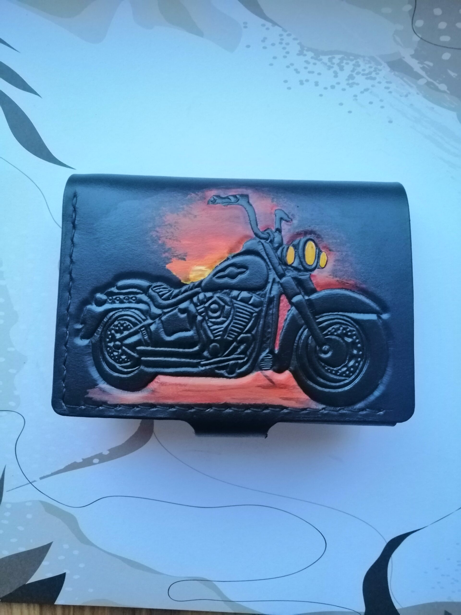 portfel z tłoczonym i malowanym wzorem  motocyklowym na tle zachodzącego słońca